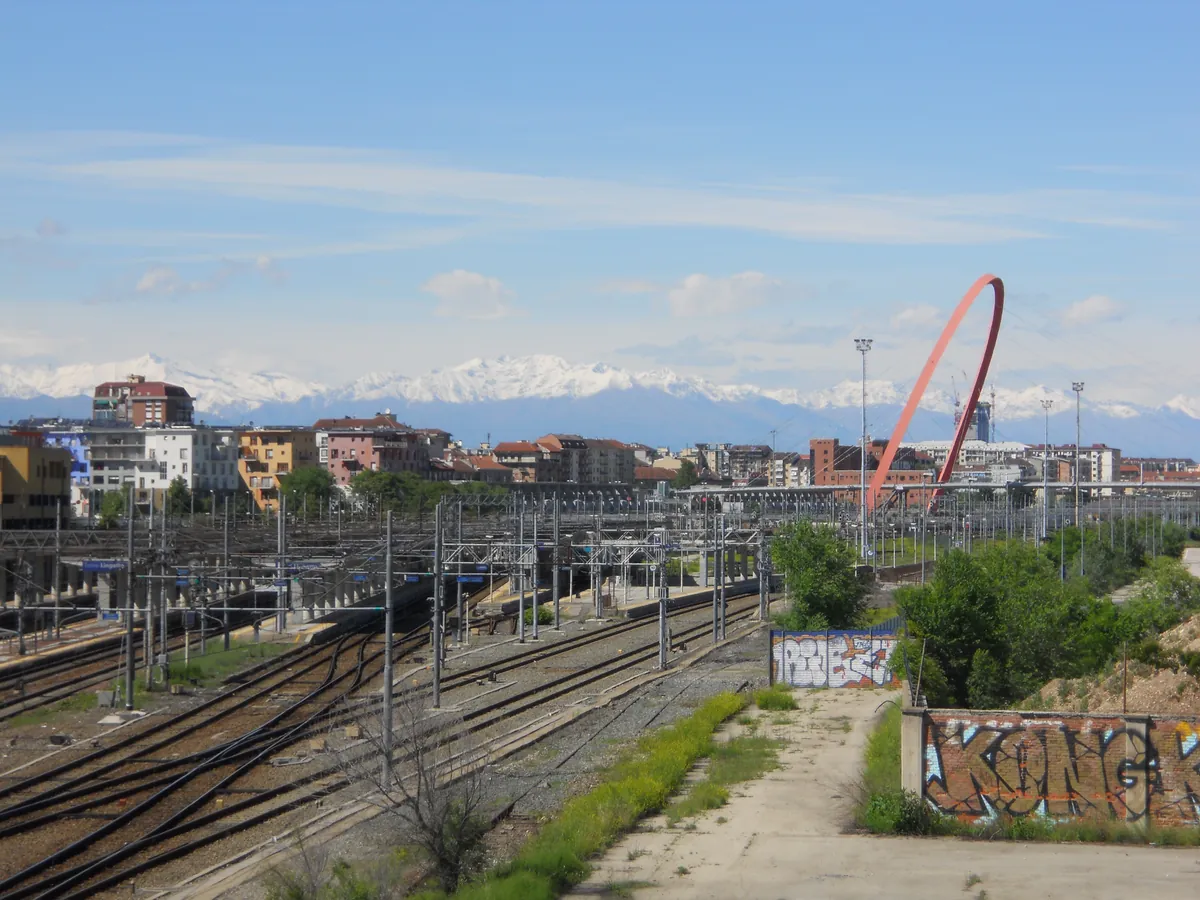 L'arco olimpico rosso sopra i binari del Lingotto, con le Alpi sullo sfondo