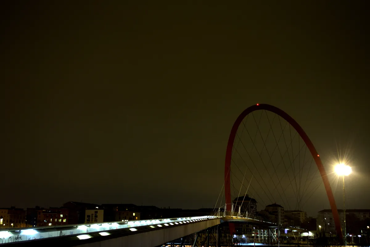 Il camminamento illuminato della Passerella Olimpica di sera, con l'arco rosso delle Olimpiadi 2006