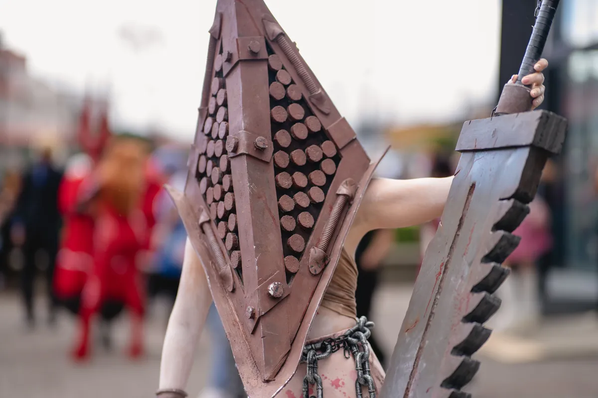 Cosplayer con una grande spada di scena tra il pubblico di un raduno all'aperto