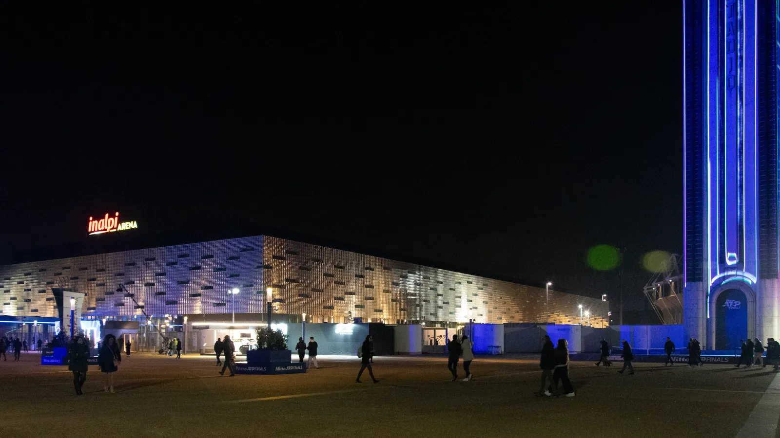L'Inalpi Arena di Torino illuminata di sera durante le ATP Finals, con il pubblico sul piazzale