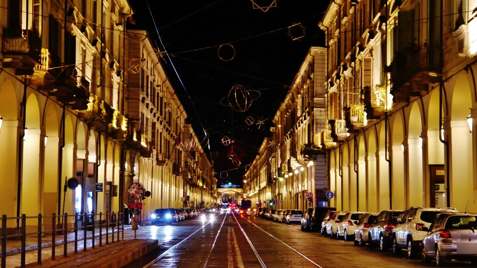 Via Po di sera, con i portici illuminati su entrambi i lati e i binari del tram